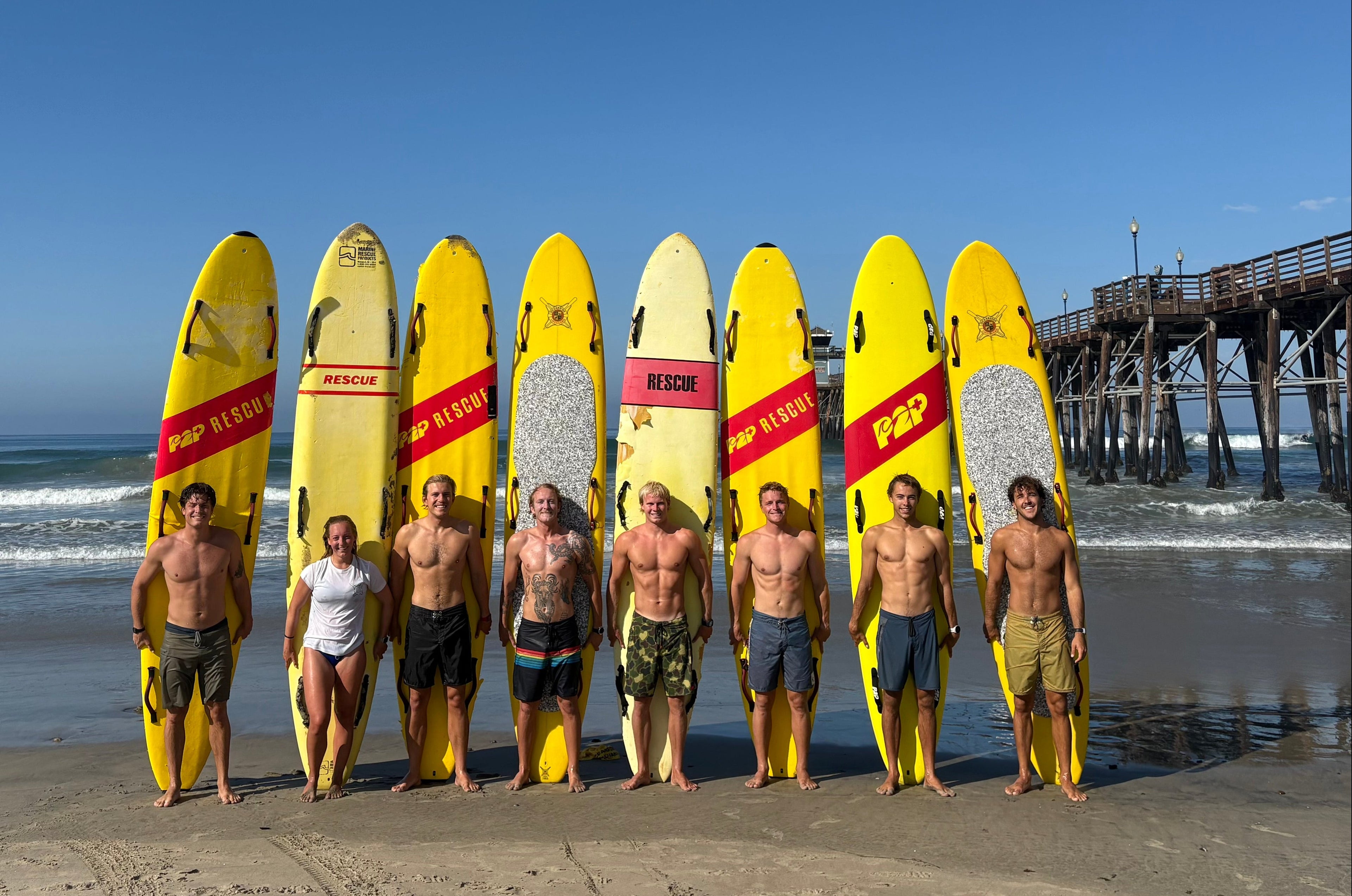 Lifeguards paddle boards surfing waves Oceanside pier Carlsbad Surf Rescue Team